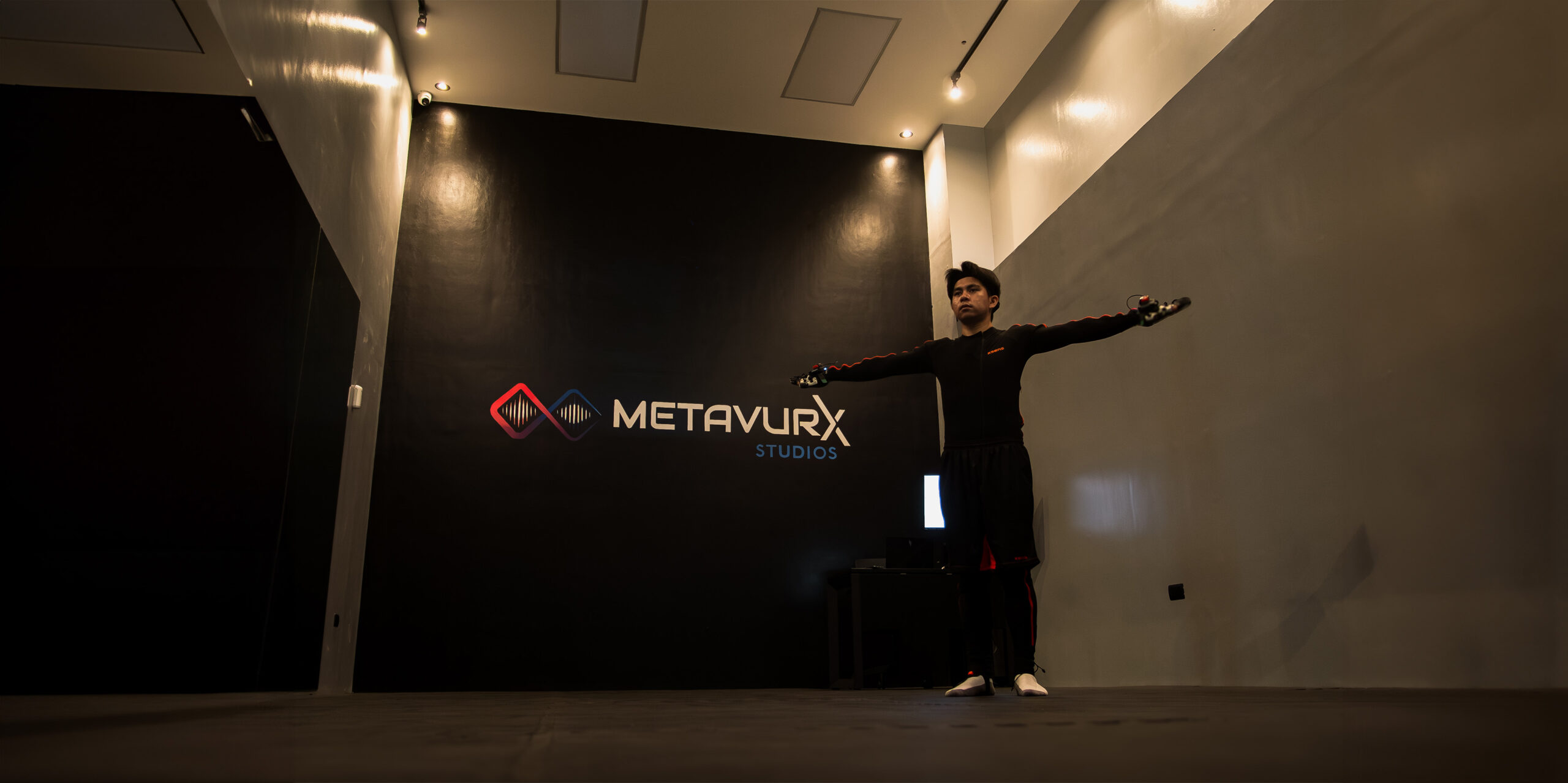 A man in an Xsens motion capture suit, doing t-pose calibrating inside the Metavurx Studios Mocap Facility.